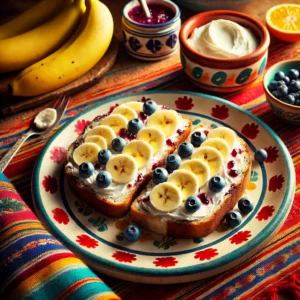 Romige krentenbroodjes, besmeerd met roomkaas en belegd met plakjes banaan, licht besprenkeld met citroensap, geserveerd op een kleurrijk keramisch bord met Mexicaanse patronen, omringd door verse bananen, roomkaas en een citroenpartje op een felgekleurd geweven tafelkleed.