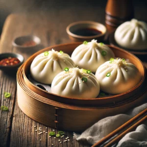 Gestoomde Ba Bao broodjes met gehaktvulling, geserveerd in een bamboestomer en gegarneerd met sesamzaadjes en lente-ui, met een schaaltje sojasaus en chili-olie aan de zijkant.