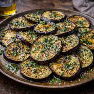 Gebakken aubergines in een schaal op rustieke houten tafel met kruiden en azijn