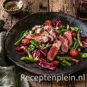 Lauwwarme salade met lamsfilet op rustieke houten tafel